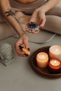 Kaboompics - Woman Holding Sage and Crystal Beside a Candle Tray