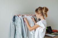 Kaboompics - Teen Girl Choosing a White Blouse from a Clothing Rack, Bedroom Fashion Lifestyle