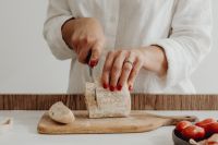 Kaboompics - Slicing a Rustic Bread Loaf on a Wooden Board