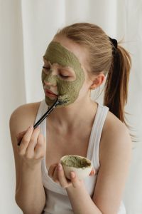 Kaboompics - Woman Applying Green Clay Mask with a Brush in a Skincare Session