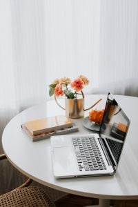 Kaboompics - Laptop Workspace with Notebook and Carnations on a Round Table
