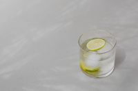 Kaboompics - Minimal Glass of Lime Water with Ice on White Surface, Soft Summer Shadows and Copy Space
