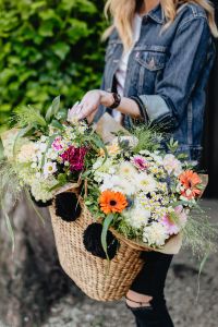 Kaboompics - Woman Arranging Colorful Flowers in a Wicker Basket