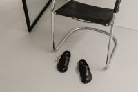 Kaboompics - Black Leather Mules in Minimal Chair Setting