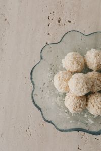 Kaboompics - Scalloped Glass Dish of Coconut Truffles on Pale Stone, Overhead Food Background with Open Space