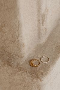 Kaboompics - Minimalist Gold and Silver Rings on Textured Beige Stone, Neutral Jewelry Background