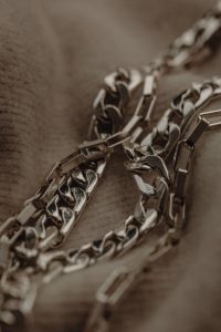 Kaboompics - Silver Chain Layers on a Neutral Fabric Background