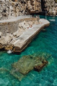 Kaboompics - Sunbathers on a Stone Seawall beneath Amalfi Coast Cliffs