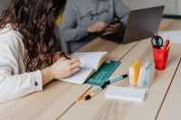 Kaboompics - Woman Writing at Desk with Man Using Laptop