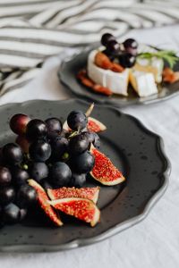 Kaboompics - Foreground Grapes and Figs with Camembert Platter in Background