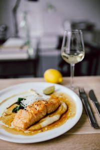 Kaboompics - Vertical Salmon Dinner Plate with White Wine and Lemon in Restaurant Setting