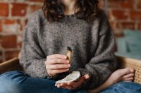 Kaboompics - Woman in a Gray Knit Sweater Holding a Palo Santo Stick beside a Brick Wall