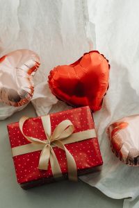 Kaboompics - Heart Balloons and Wrapped Red Gift on a White Fabric Background