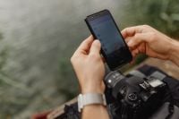 Kaboompics - Photographer Using Phone over DSLR Camera by Lake