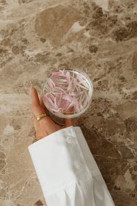 Kaboompics - Minimal Glass of Pink Petals Held over Marble Background