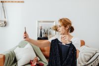 Kaboompics - Small Fashion Business Owner Showing a Navy Dress on Her Phone at Home