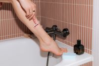 Kaboompics - Woman Shaving Her Leg with Pink Razor in Bathroom