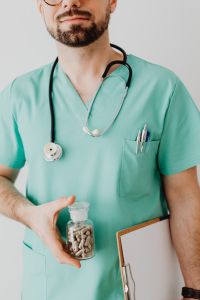 Kaboompics - Doctor Holding Medicine Bottle and Clipboard