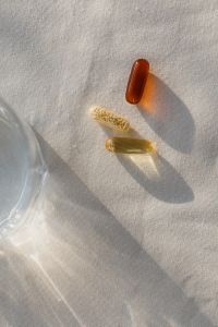 Kaboompics - Amber and Herbal Capsules with Glass of Water