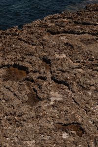 Kaboompics - Cracked Rock Surface with Small Pale Pebbles at the Edge