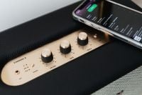 Kaboompics - Black speaker on marble table, white wall, mobile phone