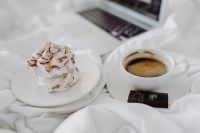 Kaboompics - Macbook, a coffee, a chocolate, a meringue dessert and a notebook in a bed