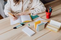 Kaboompics - Woman Writing in Notebook at Desk with Books