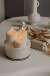 Kaboompics - Lit Pillar Candles Beside Wrapped Christmas Gift, Cozy Neutral Holiday Table