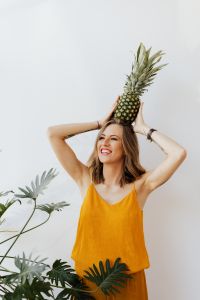 Kaboompics - Woman Balancing Pineapple above Her Head with Both Hands, Yellow Shirt Lifestyle Portrait