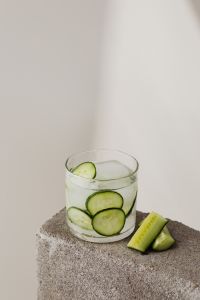 Kaboompics - Cucumber and Lime Detox Water on a Textured Stone Pedestal, Vertical Product Photo with Large White Copy Space