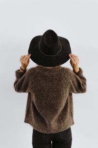 A woman in a brown sweater with a black hat on her head
