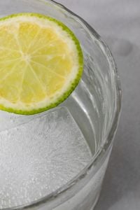 Kaboompics - Macro Lime Slice and Ice in Clear Water, Fresh Citrus Drink Detail on Pale Marble