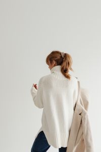 Kaboompics - Rear View of Faceless Woman in White Sweater Holding Beige Coat