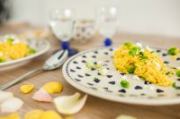 Kaboompics - Yellow rice with greens on a cute plate with blue hearts and a table decorated with flower petals
