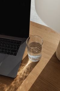 Kaboompics - Sunlit Laptop Workspace with Water Glass and Window Shadows