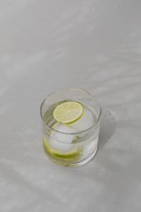 Kaboompics - Small Glass of Lime Water with Ice on Pale Marble, Vertical Minimal Drink Photo