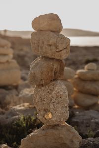 Kaboompics - Gold Necklace on Stacked Stones by the Mediterranean Sea