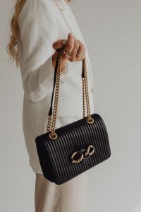 Kaboompics - Woman in White Blazer Holding Black Ribbed Chain Strap Handbag at Her Side