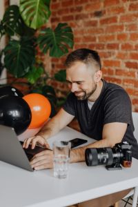 Kaboompics - Photographer Working on Laptop with Camera and Halloween Balloons