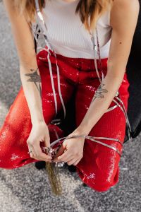 Kaboompics - Woman Tying Silver Party Streamers over Red Sequin Pants