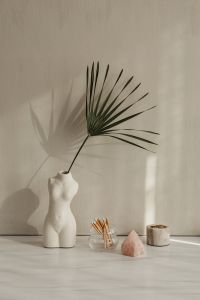 Kaboompics - White Torso Vase With Palm Leaf, Matchsticks, Rose Quartz, and Candle