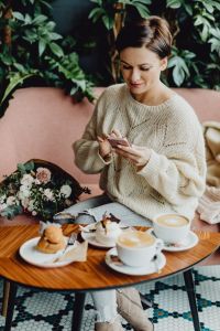 Kaboompics - Woman Using a Smartphone at a Cafe Table with Coffee and Desserts