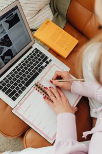 Kaboompics - Overhead View of Woman Writing in Planner with Laptop
