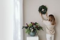 Kaboompics - Woman Hanging Wreath With Wall Copy Space