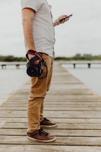 Kaboompics - Photographer Holding Camera and Phone on a Wooden Pier