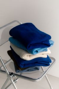 Kaboompics - Folded Winter Sweaters on an Acrylic Chair for Cozy Home Aesthetic