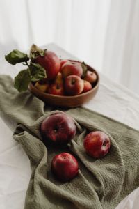 Kaboompics - Apples in a Wooden Bowl with Loose Red Fruit on White Linen, Bright Food Styling Background