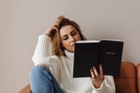 Kaboompics - Woman Reading the Bible with One Knee Raised on Sofa