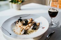 Kaboompics - Close-Up of Seafood Risotto with Mussels on a White Plate beside Red Wine