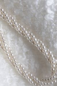 Kaboompics - Layered Pearl Strands on Textured White Fabric, Close-Up